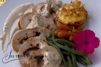 Table de réception élégamment dressée avec chandeliers, fleurs pourpres et vaisselle raffinée dans une salle lumineuse.