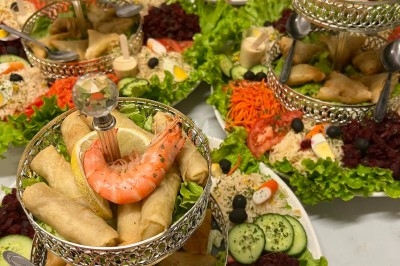 Table de réception élégamment dressée avec chandeliers, fleurs pourpres et vaisselle raffinée dans une salle lumineuse.
