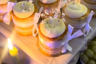 Table de réception élégamment dressée avec chandeliers, fleurs pourpres et vaisselle raffinée dans une salle lumineuse.