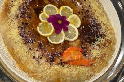 Table de réception élégamment dressée avec chandeliers, fleurs pourpres et vaisselle raffinée dans une salle lumineuse.