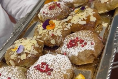 Table de réception élégamment dressée avec chandeliers, fleurs pourpres et vaisselle raffinée dans une salle lumineuse.