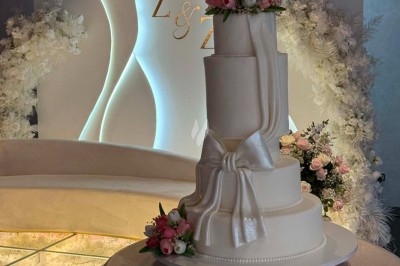 Table de réception élégamment dressée avec chandeliers, fleurs pourpres et vaisselle raffinée dans une salle lumineuse.