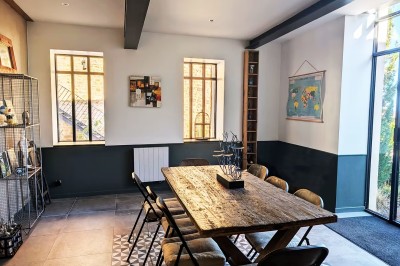Deux chaises en rotin et une table ronde sur une terrasse ensoleillée avec des ombres marquées au sol.