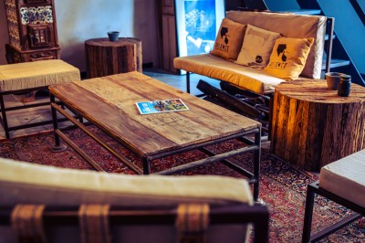 Deux chaises en rotin et une table ronde sur une terrasse ensoleillée avec des ombres marquées au sol.