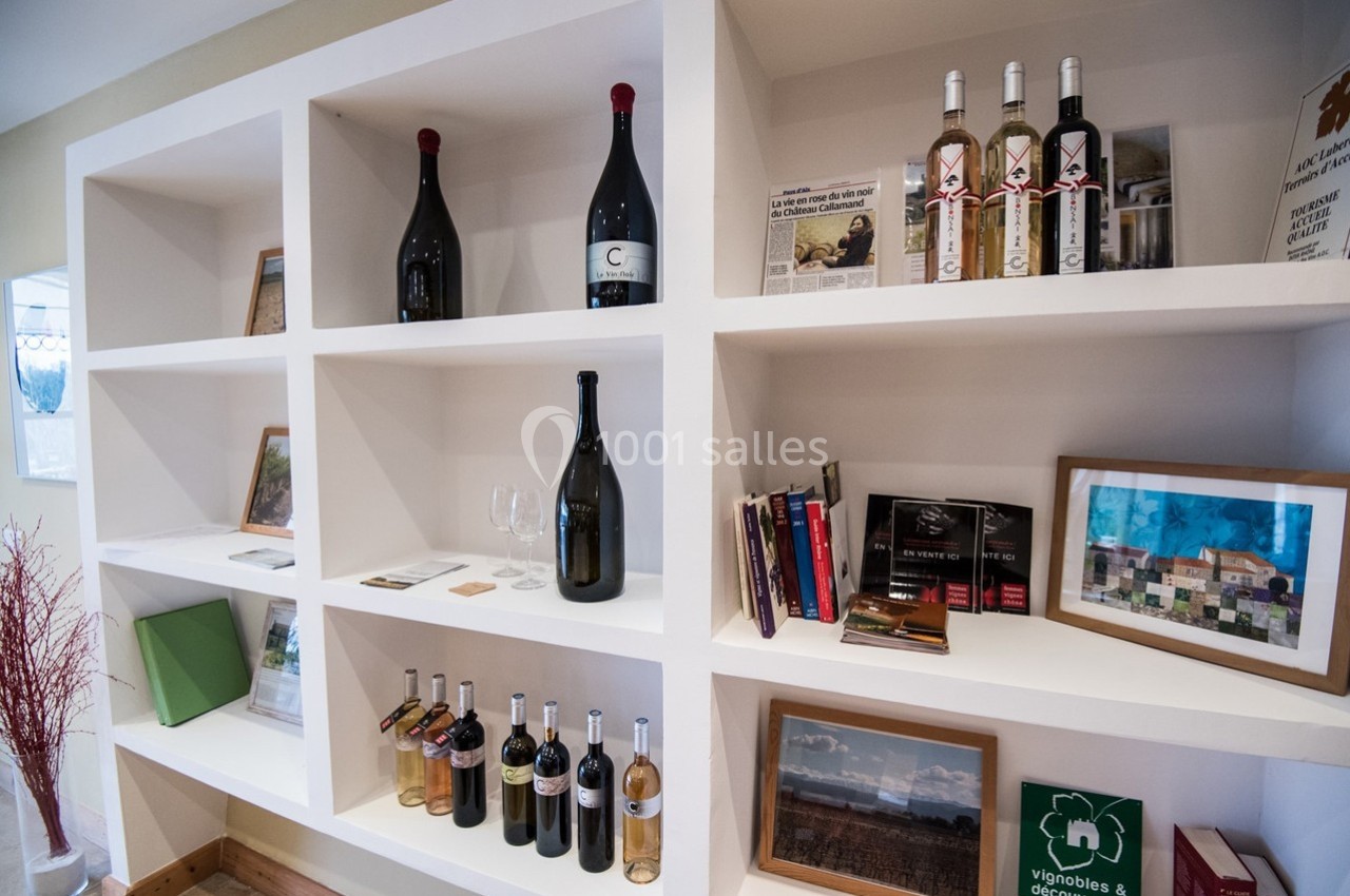 Étagères blanches contenant des bouteilles de vin, livres, cadres photo et divers objets décoratifs.