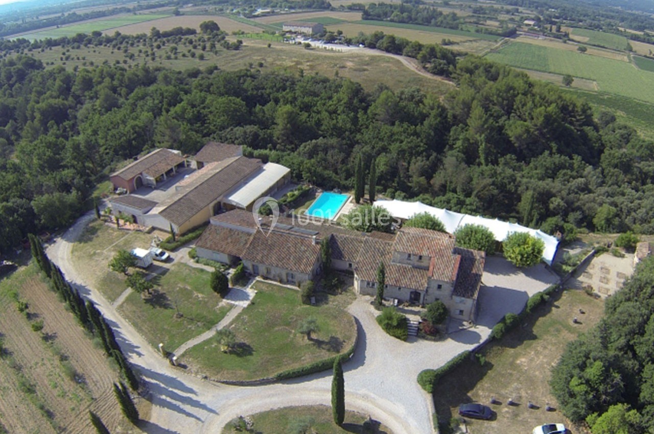 Vue aérienne d'un domaine rural avec bâtiments en pierre, piscine, arbres et champs environnants.