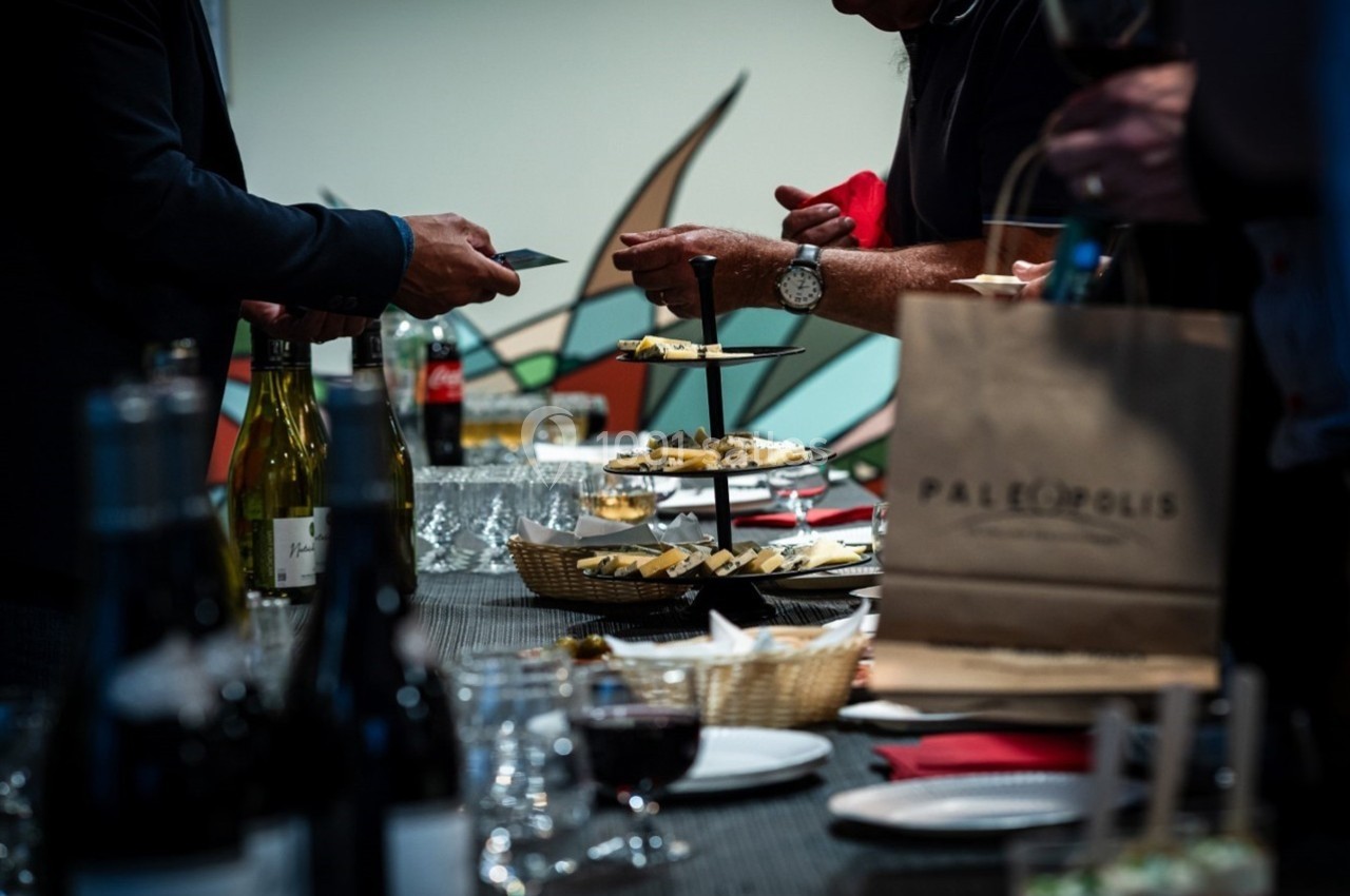 Location salle Gannat (Allier) - Paléopolis #9 Personnes se servant de nourriture et de boissons sur une table garnie lors d'un événement ou d'une réception.