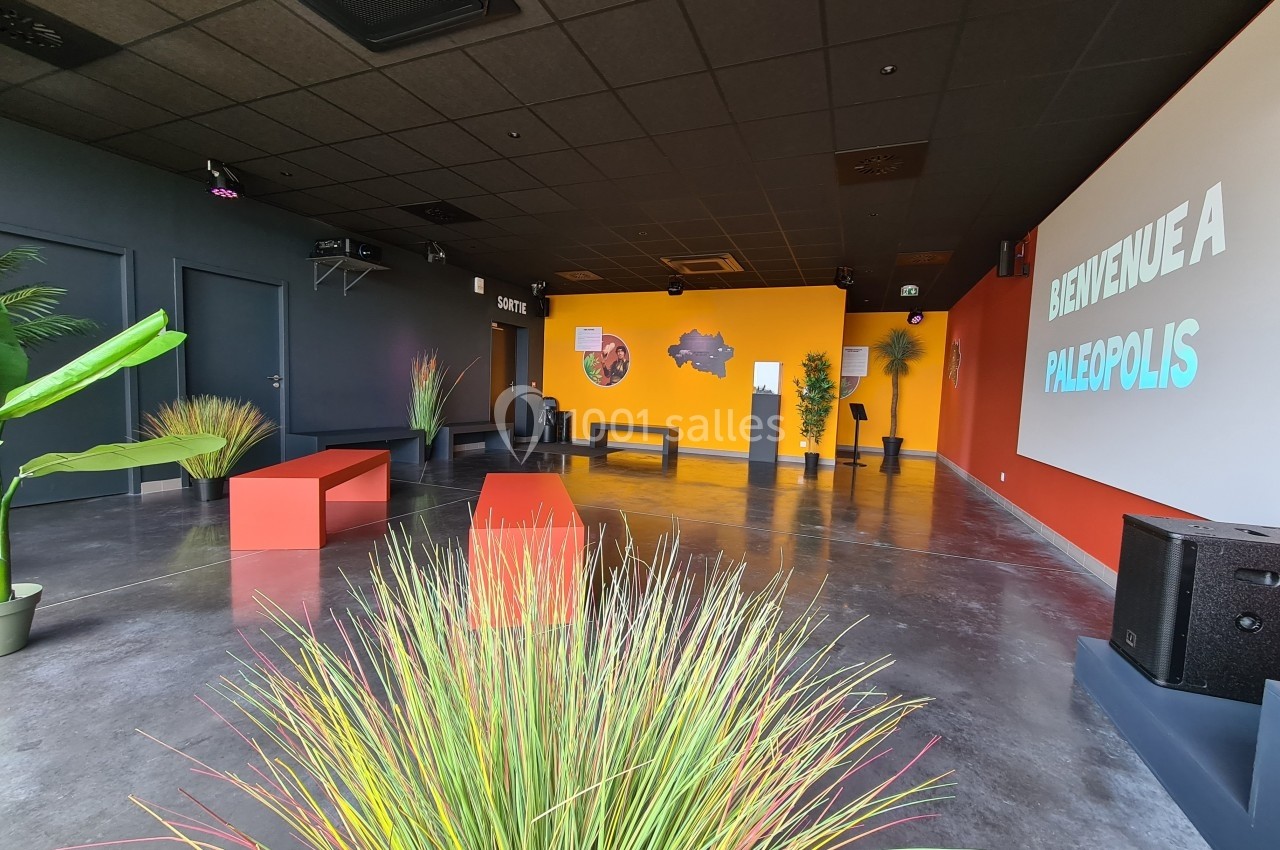Location salle Gannat (Allier) - Paléopolis #2 Salle d'accueil moderne avec bancs colorés, plantes décoratives et un écran affichant ’Bienvenue à Paléopolis’.