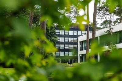 Miniature Le bâtiment du WIP Femme assise dans un hammam aux carreaux roses, enveloppée dans une serviette blanche.