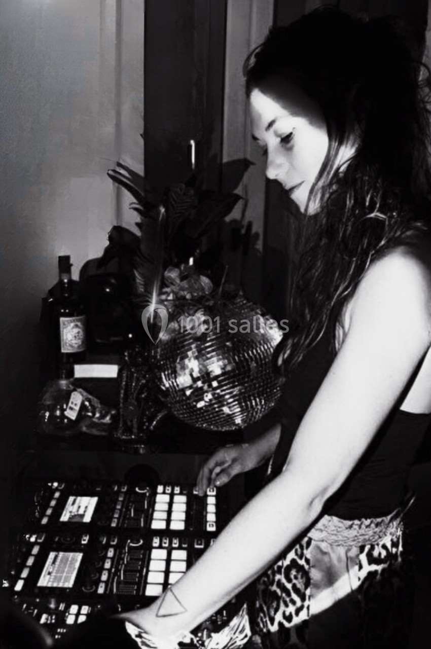 Femme utilisant un équipement de mixage audio dans un environnement intérieur faiblement éclairé.