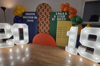 Mur décoratif coloré avec motifs africains, ballons et panneaux portant des messages inspirants en anglais.