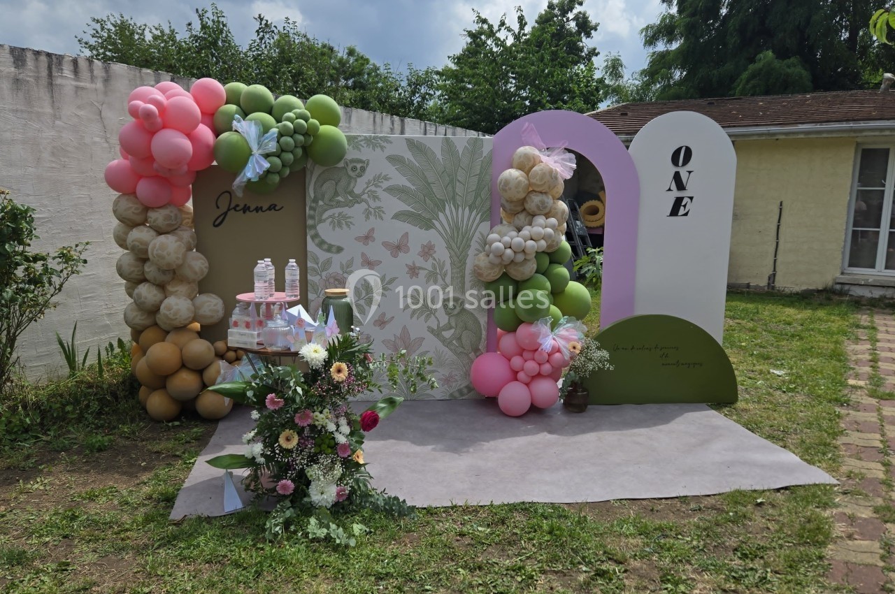 Décoration festive en extérieur avec ballons colorés, fleurs et panneaux pour un premier anniversaire.