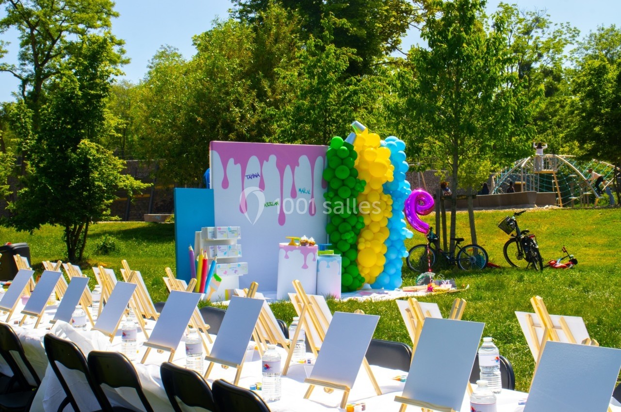 Décoration colorée avec ballons et chevalets installés pour une activité en plein air dans un parc verdoyant.