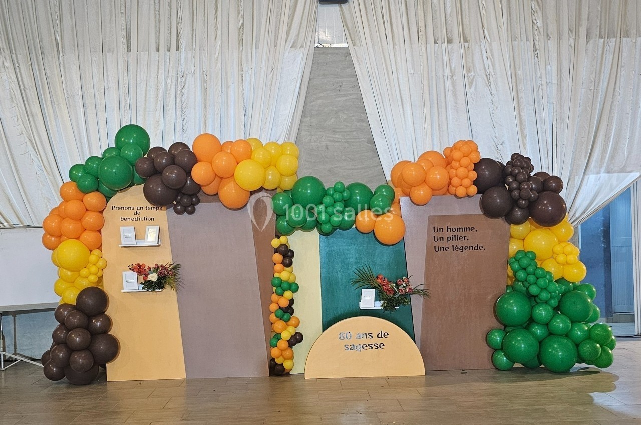 Décor festif avec des ballons colorés et des panneaux commémoratifs célébrant 80 ans de sagesse.