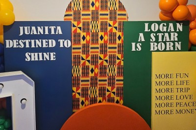 Mur décoratif coloré avec motifs africains, ballons et panneaux portant des messages inspirants en anglais.