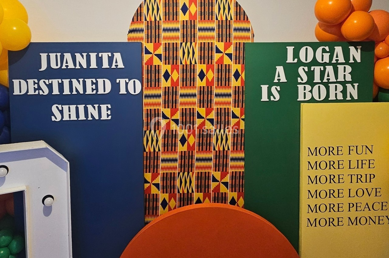 Mur décoratif coloré avec motifs africains, ballons et panneaux portant des messages inspirants en anglais.