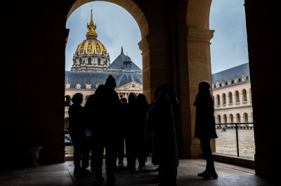 Des visiteurs lisent des informations près d'une réplique de la statue de la Liberté dans un espace intérieur lumineux.