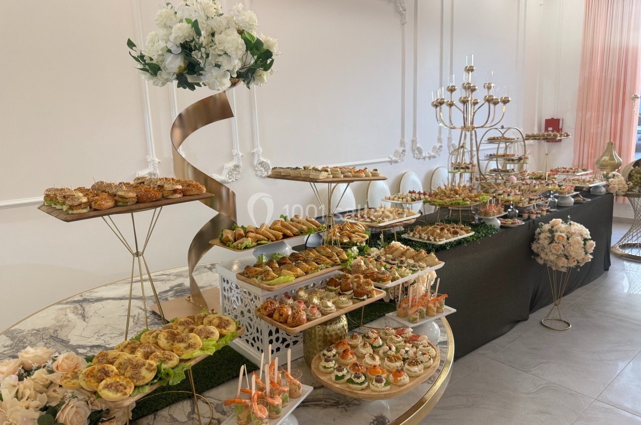 Buffet élégant avec une variété de bouchées salées et sucrées, disposées sur des tables décorées de fleurs et d'éléments…