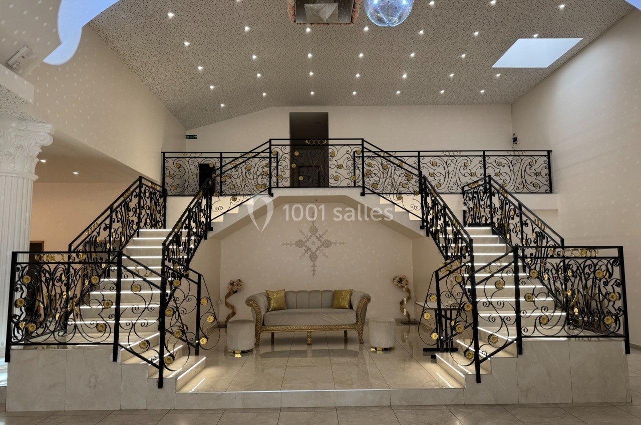 Escalier double en fer forgé avec éclairage intégré, encadrant un canapé beige dans un intérieur lumineux et élégant.
