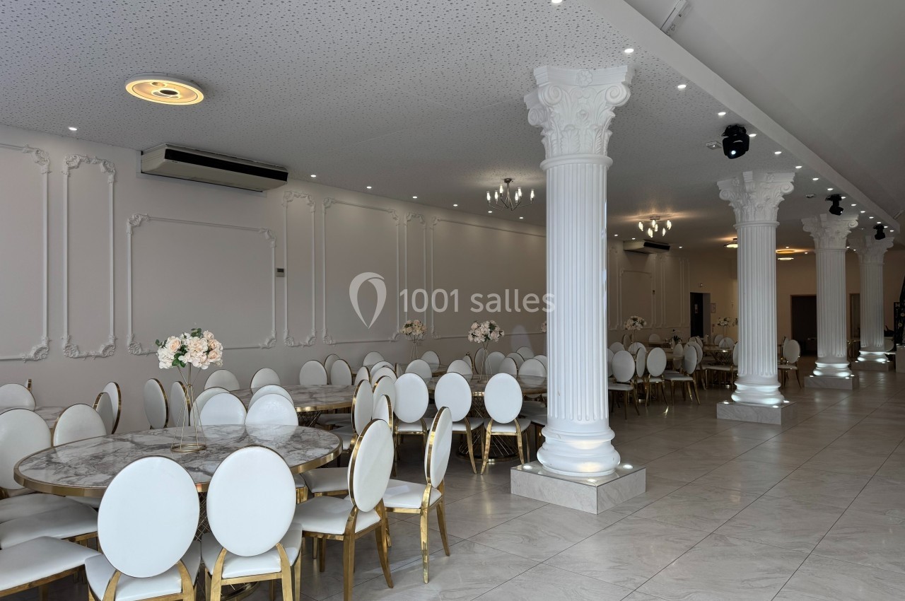 Salle de réception lumineuse avec colonnes blanches, tables rondes en marbre et chaises blanches dorées.