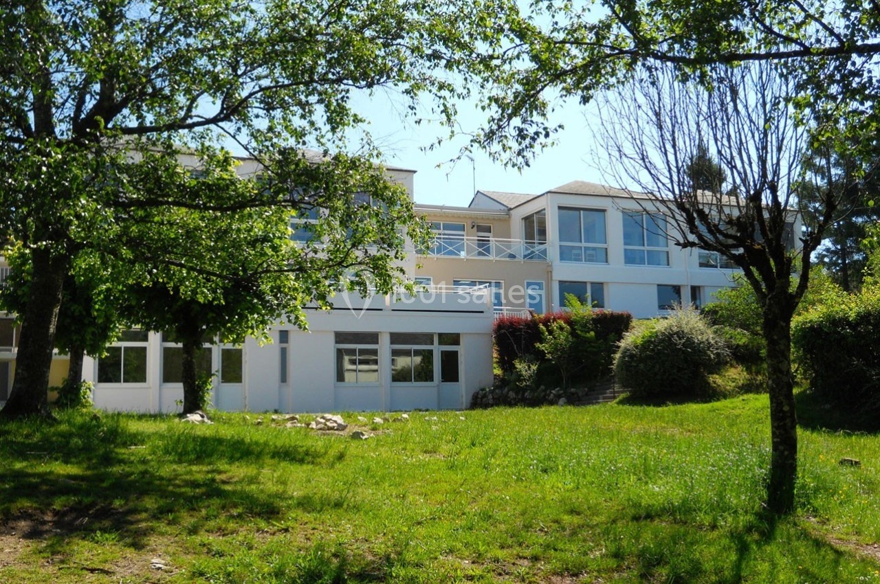 Bâtiment moderne à deux étages entouré d'arbres et de pelouse sous un ciel dégagé.
