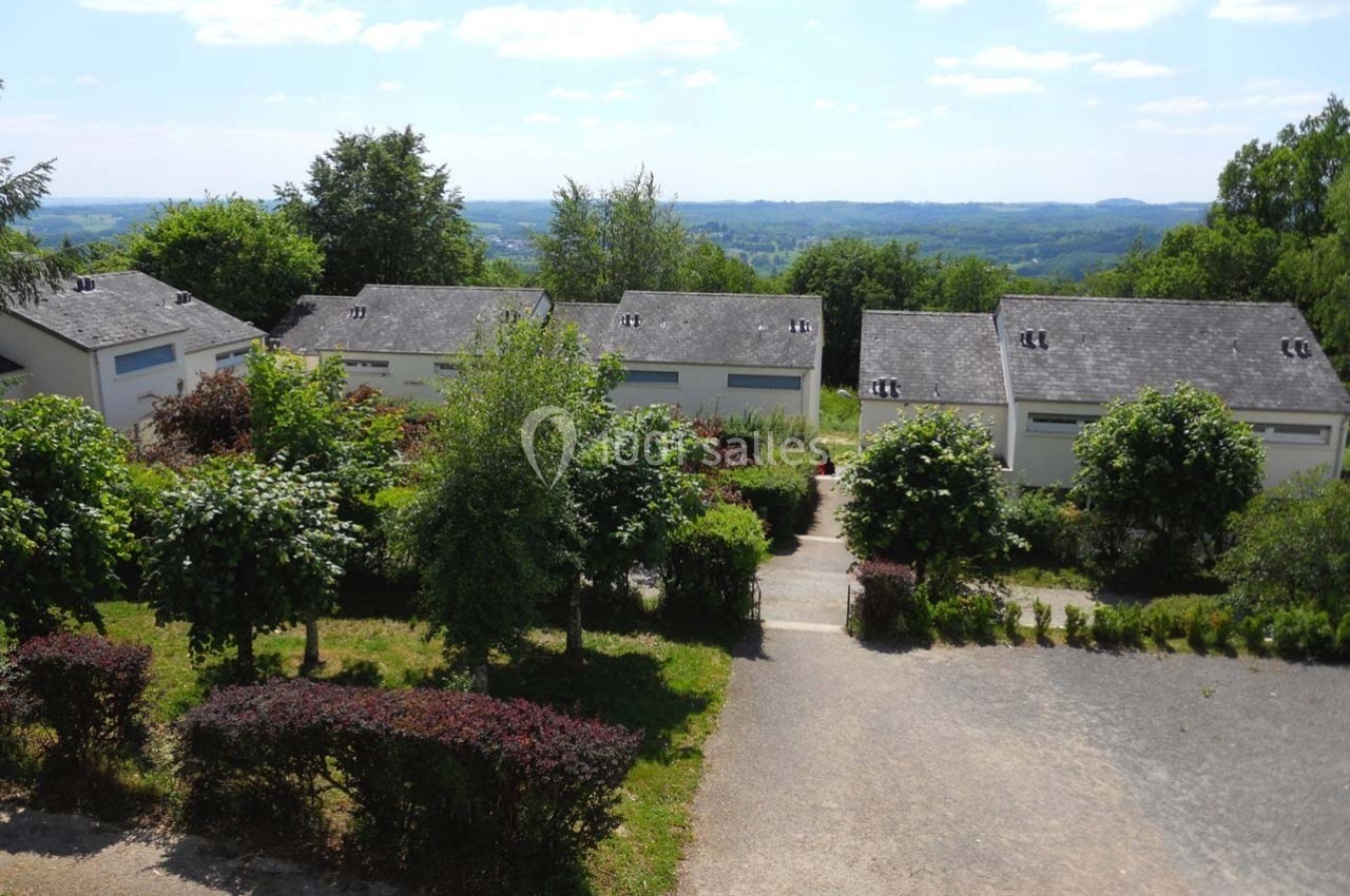 Vue de petites maisons blanches avec toits en ardoise, entourées de végétation, sous un ciel dégagé.