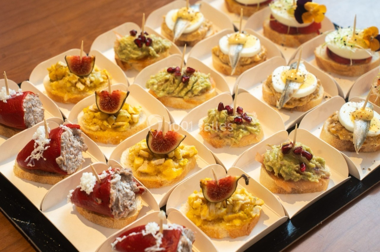 Plateau de tapas variées comprenant des toasts garnis d'avocat, figues, anchois, œufs et poivrons farcis.