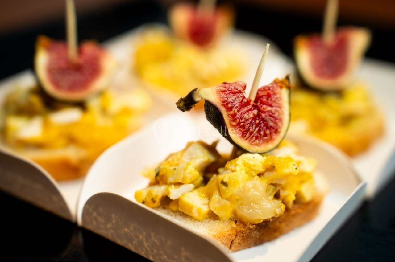 Tranches de pain garnies de salade de pommes de terre et de quartiers de figues fraîches sur des pics en bois.