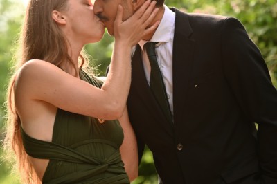 Un homme souriant tenant un appareil photo sur un chemin bordé d'arbres.
