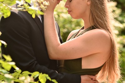 Un homme souriant tenant un appareil photo sur un chemin bordé d'arbres.