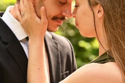 Un homme souriant tenant un appareil photo sur un chemin bordé d'arbres.