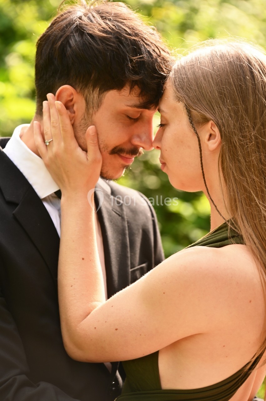 Un couple se tient tête contre tête dans un moment tendre, entouré d'un arrière-plan naturel flou.