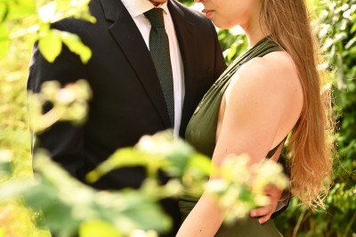 Un homme souriant tenant un appareil photo sur un chemin bordé d'arbres.