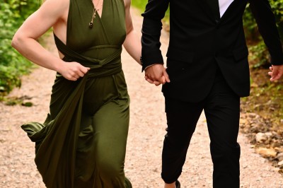 Un homme souriant tenant un appareil photo sur un chemin bordé d'arbres.