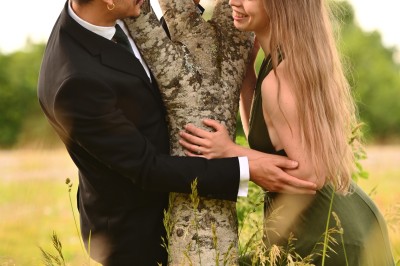 Un homme souriant tenant un appareil photo sur un chemin bordé d'arbres.
