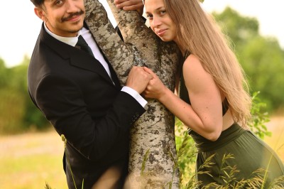 Un homme souriant tenant un appareil photo sur un chemin bordé d'arbres.