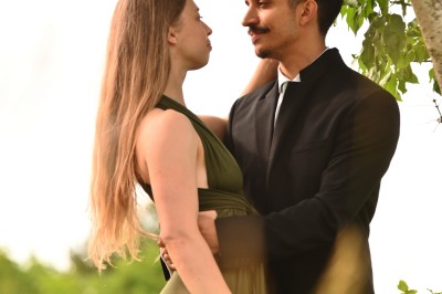 Un homme souriant tenant un appareil photo sur un chemin bordé d'arbres.