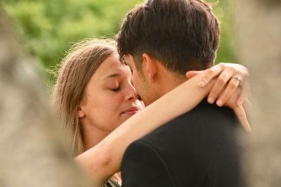 Un homme souriant tenant un appareil photo sur un chemin bordé d'arbres.