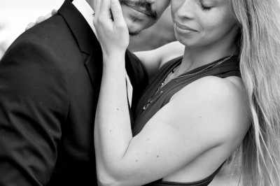 Un homme souriant tenant un appareil photo sur un chemin bordé d'arbres.