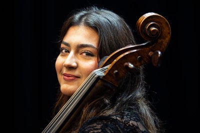Un homme souriant tenant un appareil photo sur un chemin bordé d'arbres.