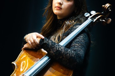 Un homme souriant tenant un appareil photo sur un chemin bordé d'arbres.