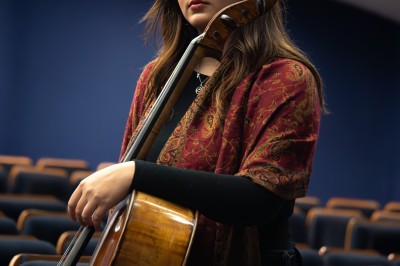 Un homme souriant tenant un appareil photo sur un chemin bordé d'arbres.