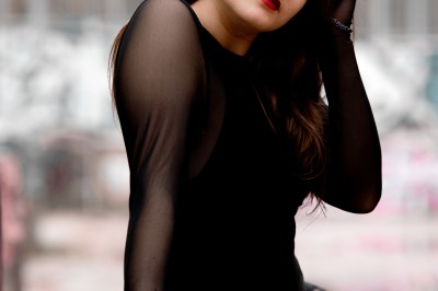 Un homme souriant tenant un appareil photo sur un chemin bordé d'arbres.