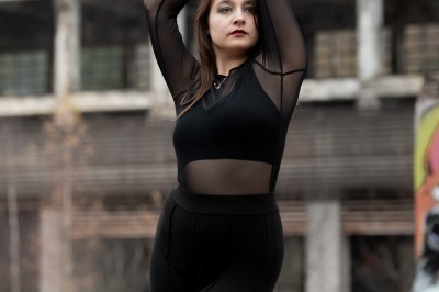 Un homme souriant tenant un appareil photo sur un chemin bordé d'arbres.