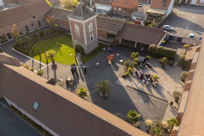 Un DJ mixe en extérieur, portant un casque audio et des lunettes de soleil, avec un mur de briques en arrière-plan.