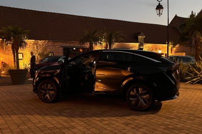 Miniature Location salle Cantin (Nord) - Le Clos du Colombier #24 SUV vert exposé dans une salle avec parquet et murs en bois, accompagné de panneaux promotionnels en arrière-plan.