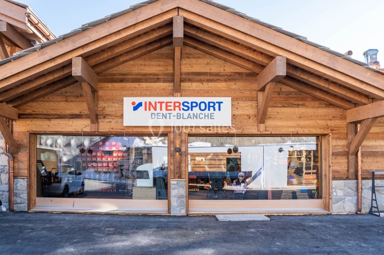 Façade d'un magasin Intersport Dent-Blanche avec une structure en bois et de grandes vitrines.