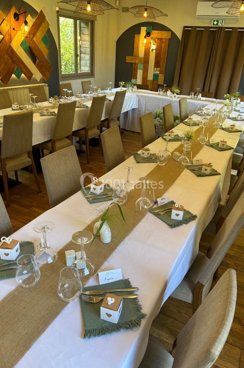 Salle de réception avec tables dressées, nappes blanches, chemins de table en jute et décorations élégantes.