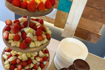 Plateau à trois étages avec fraises et morceaux de fruits, accompagné d'une fontaine de chocolat sur une table.
