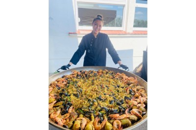 Burger au saumon fumé avec laitue, tomate et sauce, posé sur une table en marbre avec citron vert et herbes en arrière-plan.